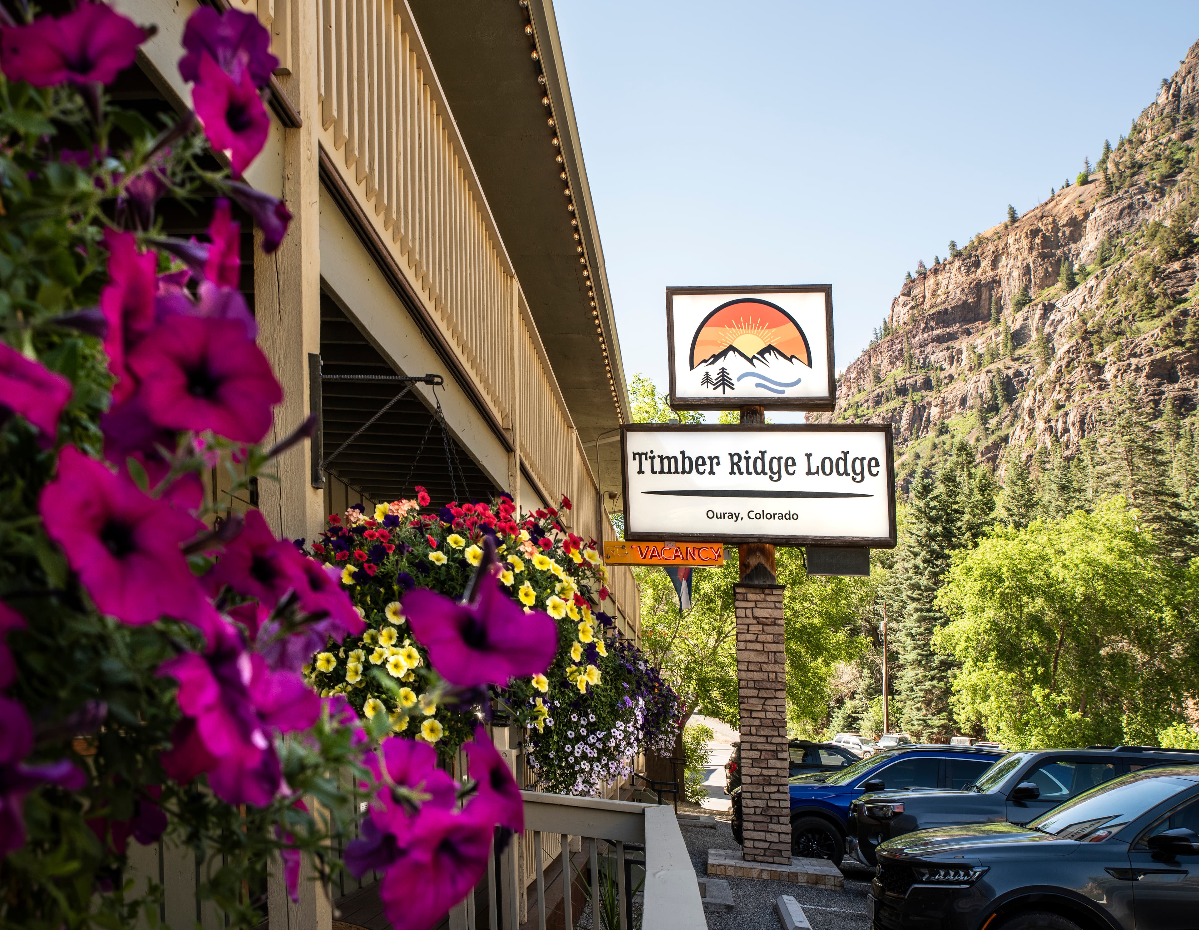 Sign for Timber Ridge Lodge in Ouray, Colorado, with colorful flowers and mountains in the background.