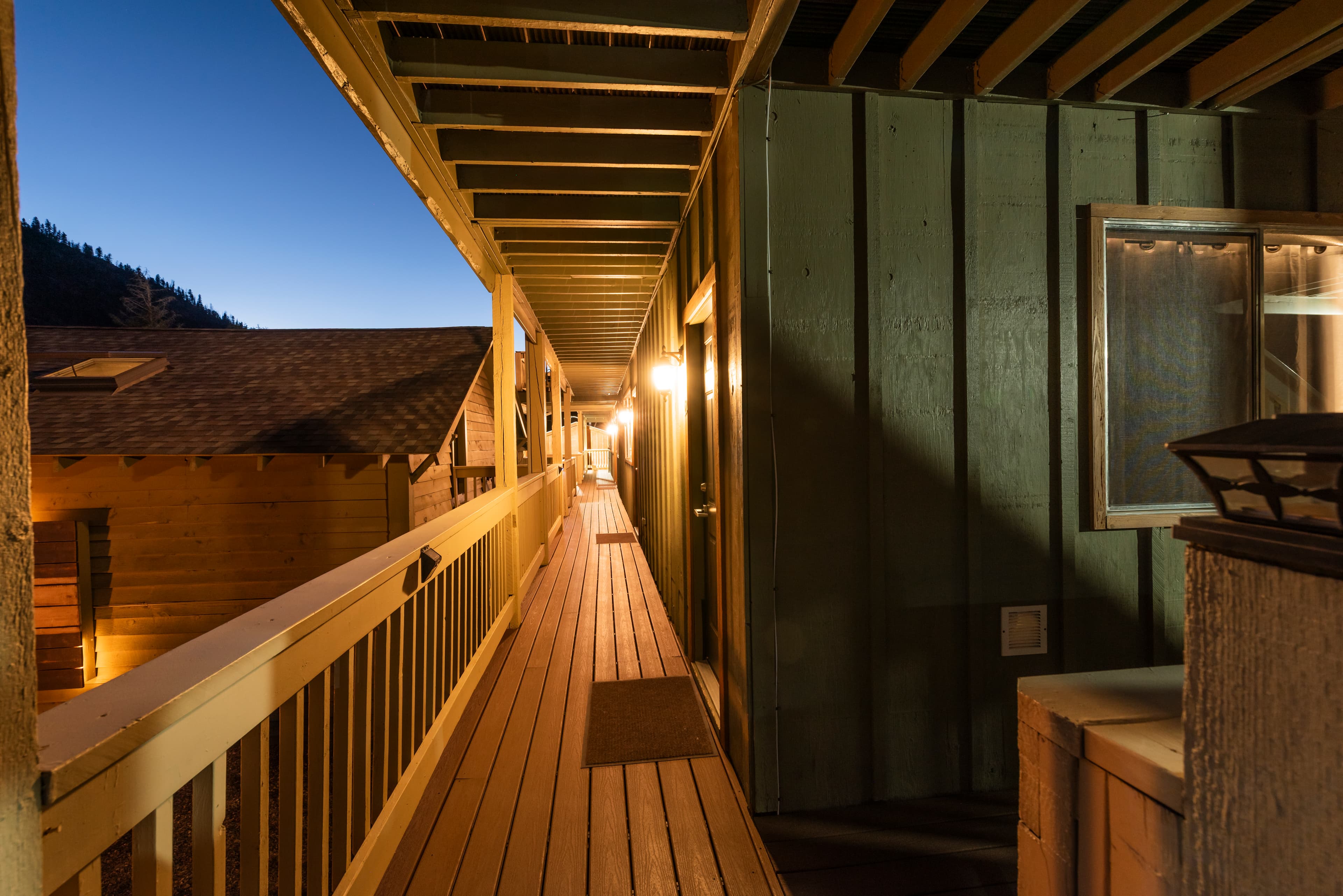 A dimly lit wooden balcony overlooking buildings at dusk.
