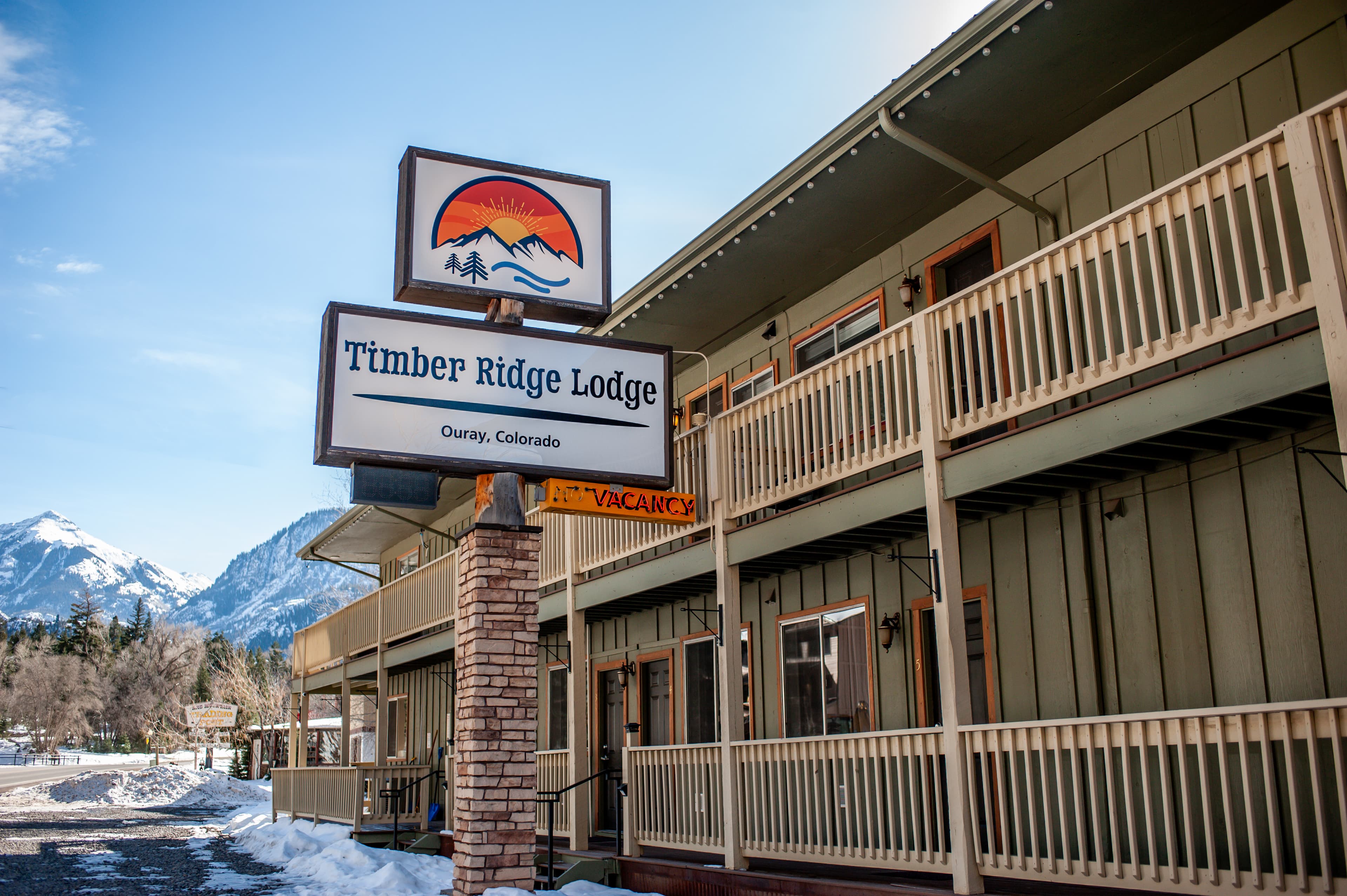 Sign for Timber Ridge Lodge in Ouray, Colorado, with snowy mountains in the background.