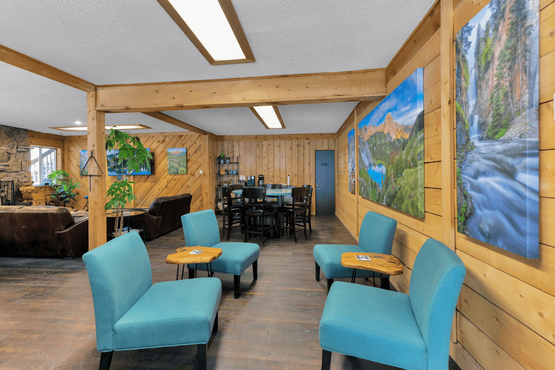 Cozy lounge area with wooden walls, blue chairs, and nature-themed artwork.