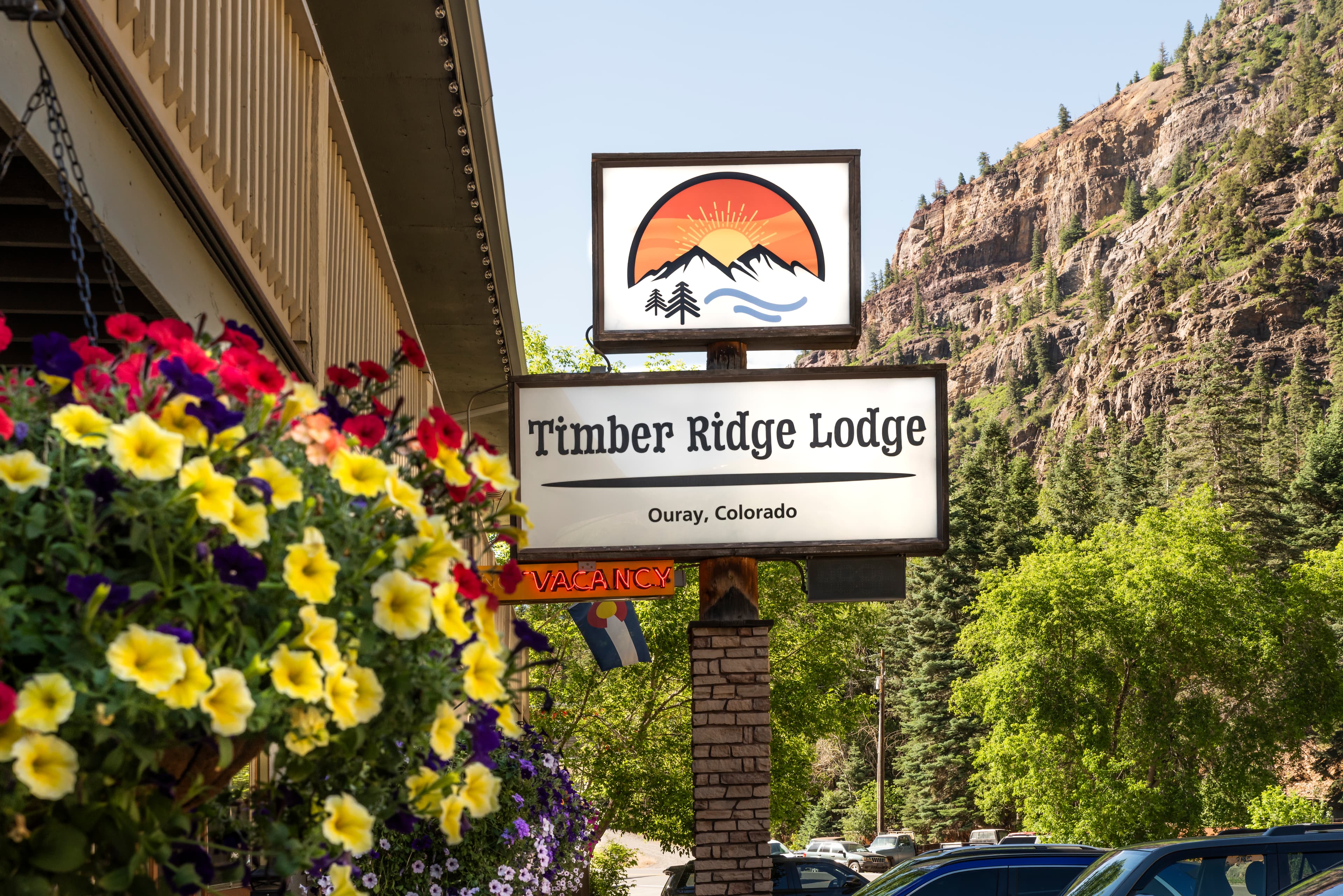 Sign for Timber Ridge Lodge in Ouray, Colorado, surrounded by flowers and mountains.